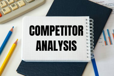 Ofis masasında kırtasiye arasında COMPETITOR ANALYSIS metni bulunan defter.