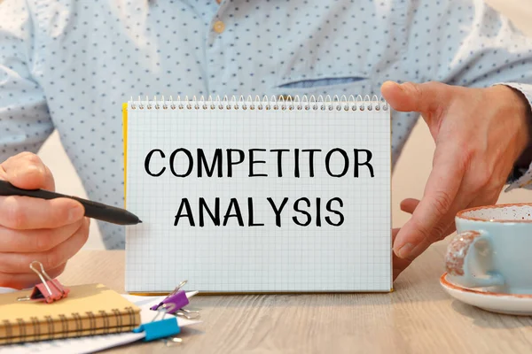 Ofis masasında kırtasiye arasında COMPETITOR ANALYSIS metni bulunan defter.