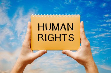 Elinde mavi gökyüzünün arka planında insan hakları yazılı bir kart tutan adam..
