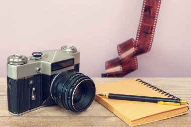 Ahşap yüzeyde eski fotoğraf makinesi ve kalem olan not defteri.