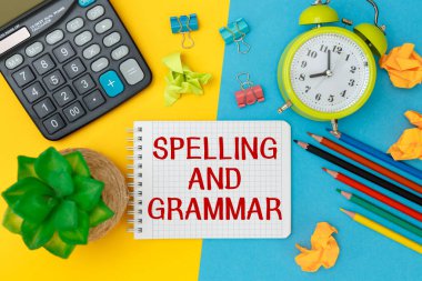 Yazım ve Gramer ofis aksesuarlarıyla birlikte bir ofis masasının üzerindeki bir not defterine yazılır..