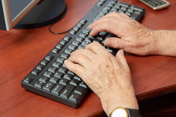 コンピューターのキーボードに入力している高齢女性の手のクローズアップショット — ストック写真