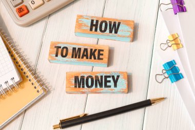 Nasıl para kazanılır? Ofis malzemelerinin yanındaki tahta bloklara yazılmış kelimeler.