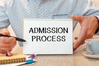 Ofis masası ve içinde metin olan defter - Ofis masasının üzerindeki kırtasiye arasında ADMISSION PROCESS.