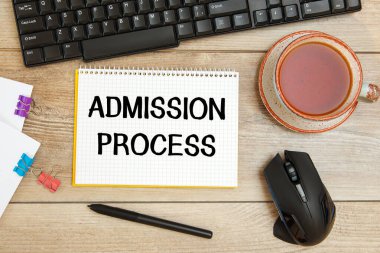 Ofis masası ve metin içeren defter - ADMISSION Prosedürleri, klavye ve bir fincan çay