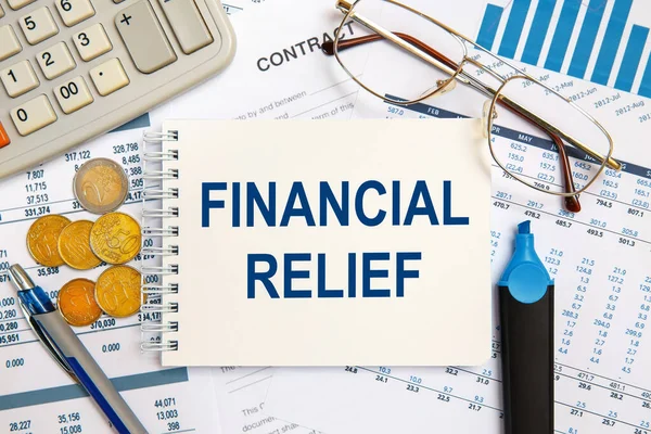 Financial Relief is written on a notepad on an office desk with office accessories.