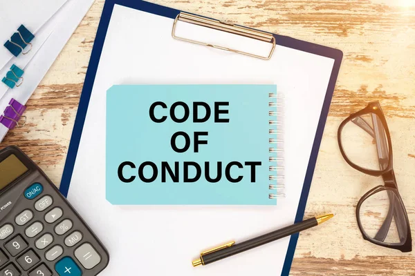CODE OF CONDUCT - an inscription on a card near office supplies and computer