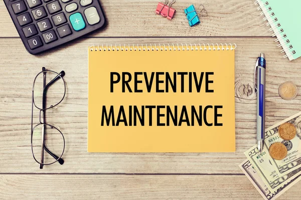 Preventive Maintenance is written on a notepad on an office desk with office accessories.