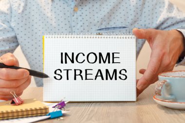 Ofis masasının üzerindeki kırtasiye malzemelerinin arasında gelir tablosu olan defter..