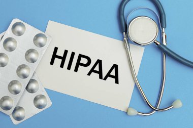Üzerinde HIPAA yazan kart 1996 Sağlık Sigortası Taşınabilirliği ve Hesaplanabilirlik Yasası, steteskop ve haplar, üst görünüm