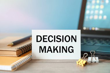 Belgeler, hesap makinesi ve not defteri olan bir masaüstü. Bir bloklama tahtası yazıtında Karar Verme