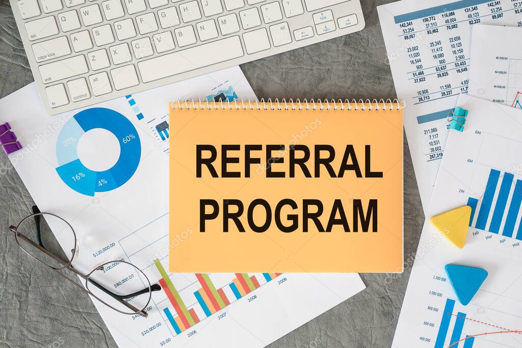 Referral program is written in a document on the office desk with office accessories.