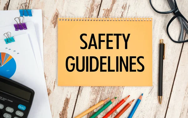 Notebook with text - Safety Guidelines, on the office table, documents, calculator, glasses and pen