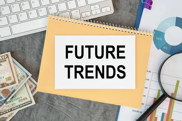 FUTURE TRENDS is written in a document on the office desk with office accessories, money, diagram and keyboard