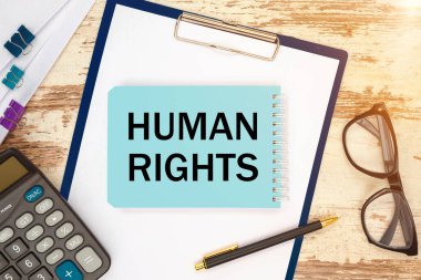 Metin içeren defter - İnsan Hakları, ofis masası, dokümanlar, hesap makinesi, gözlük ve kalem