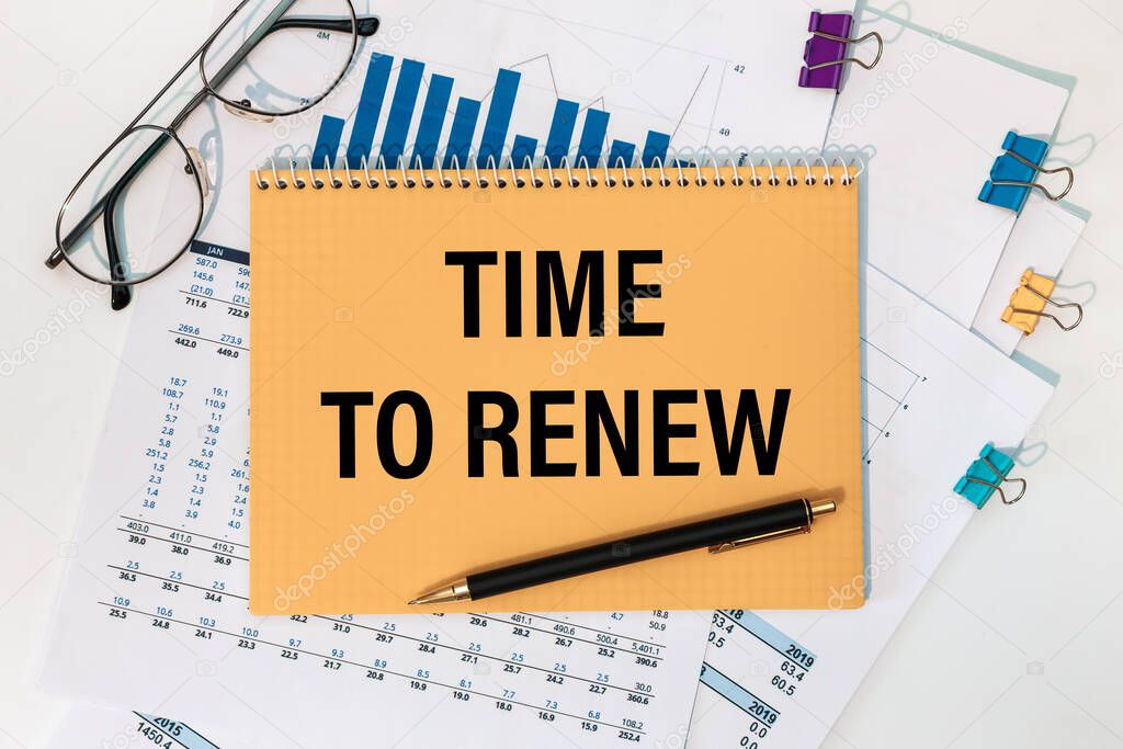 TIME TO RENEW is written on a notepad on an office desk with office accessories.