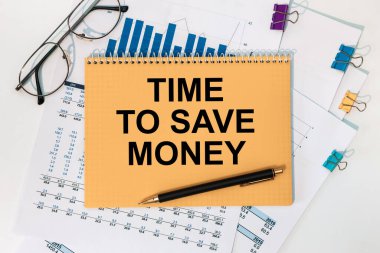 Ofis masasında kırtasiye malzemelerinin arasında para biriktirmek için kullanılacak metin zamanı olan defter..