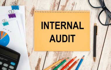 Metin içeren defter - InterTERNAL AUDIT, ofis masasının üzerinde, belgeler, hesap makinesi, gözlük ve kalem