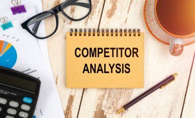 Metin içeren defter - COMPETITOR ANALYSIS, ofis masasında, belgeler, hesap makinesi, gözlük ve kalem