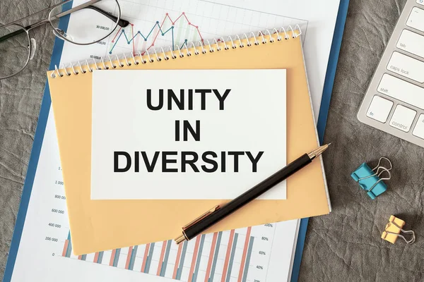 Unity in diversity is written in a document on the office desk with office accessories.