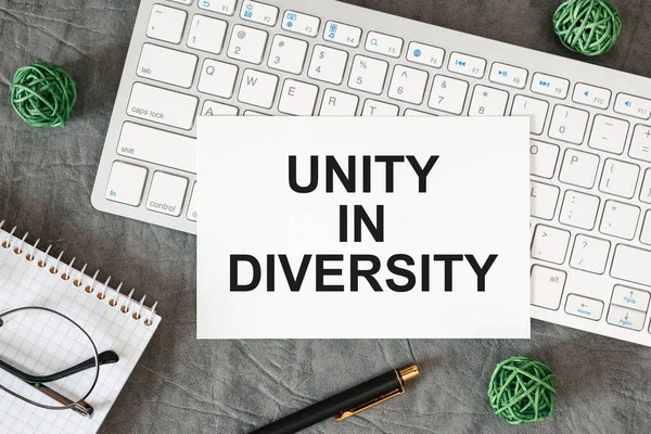 Unity in diversity is written in a document on the office desk with office accessories.