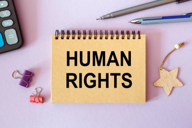 İnsan Hakları. Ofis masasındaki bir not defterine, ofis aksesuarlarıyla birlikte yazılmış..