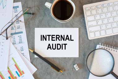 INTERNAL AUDIT ofis masasındaki bir belgede ofis aksesuarları, kahve, klavye ve akıllı