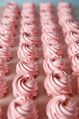 Parşömen arka planında el yapımı pembe şekerlemeler. Marshmallow, Meringue. Ev yapımı tatlı.
