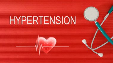 Kırmızı arka planda steteskop ve kalp şeklinde HYPERTENSION konsepti