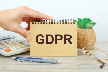 GDPR - Genel Veri Koruma Yönetmeliği bir ofis masasındaki bir not defterinde ofis aksesuarlarıyla birlikte yazılıdır.