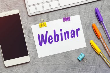 Üzerinde Webinar, klavye ve akıllı telefon metni olan bir kağıt not..