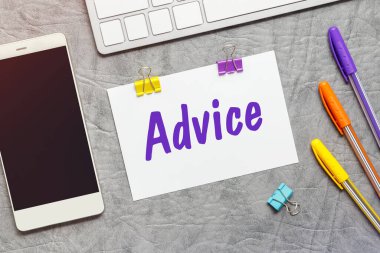 Tavsiye, klavye ve akıllı telefon metni içeren bir kağıt not.