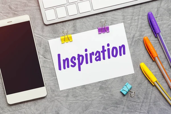 Üzerinde ilham, klavye ve akıllı telefon metni olan bir kağıt not..