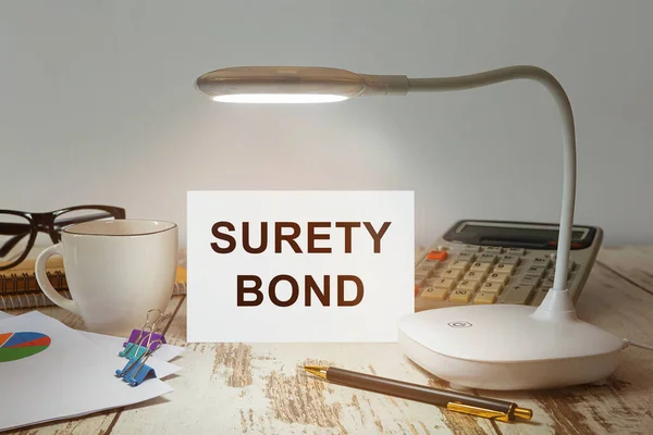 Office desk with a lamp that illuminates the inscription Surety Bond