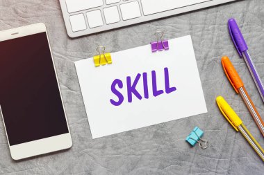 SkILL, klavye ve akıllı telefon metninin olduğu bir kağıt not..
