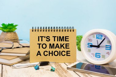 Üzerinde yazı olan bir tabela. Ofis malzemeleriyle masada bir seçim yapma zamanı.