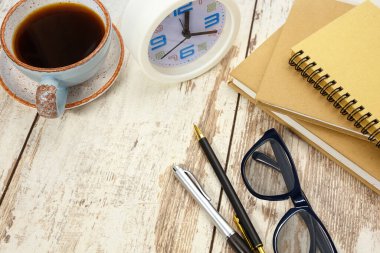 Ofis malzemeleri, not defterleri, hesap makinesi ve retro ahşap masada bir fincan kahve..