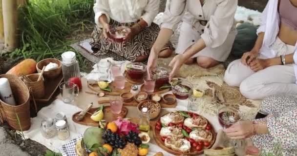 Um grupo de mulheres sentadas em uma mesa com comida e segurando pratos — Vídeo de Stock