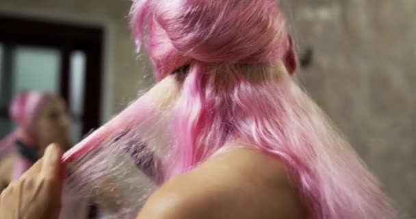 한 젊은 여자가 거울 앞에서 머리를 곧게 사용 한다. 근접 촬영 — 비디오