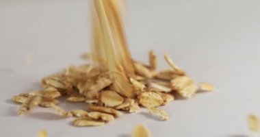 Yuvarlanan yulafların beyaz arka planda yuvarlanan yakın plan görüntüsü bir masada dönüyor.