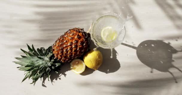 Blick von oben auf Ananas, Zitrone, Palmenschatten und ein Glas Limo — Stockvideo