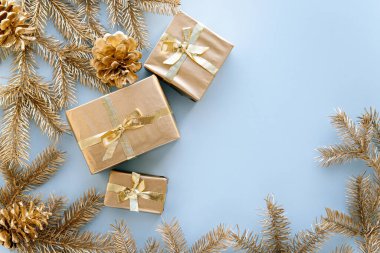 Mavi Noel ya da yeni yıl arkaplanı, altın Noel hediyelerinin ve altın köknar dallarının sade kompozisyonu, düzlük, düzlük, mesajlaşma için boş alan. Noel konsepti.