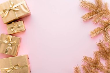 Pembe Noel veya yeni yıl arkaplanı, altın Noel hediyelerinin sade kompozisyonu ve altın köknar dalları, Flatlay, mesajlaşma için boş alan. Noel konsepti.