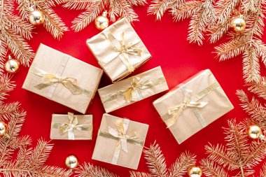 Kırmızı Noel ya da yeni yıl arkaplanı, altın Noel hediyelerinin sade kompozisyonu ve altın köknar dalları, Flatlay, mesajlaşma için boş alan. Noel konsepti.