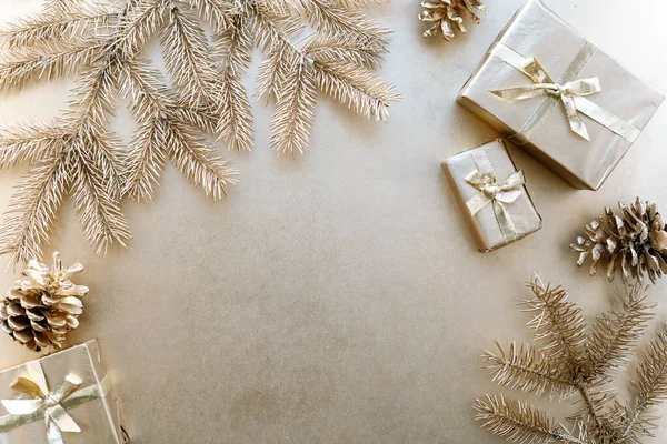 Altın Noel veya yeni yıl arkaplanı, Altın Noel hediyelerinin basit kompozisyonu, altın köknar dalları ve çam kozalakları, düzlük, mesaj atmak için boş alan.