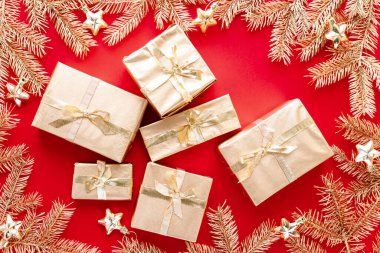 Kırmızı Noel ya da yeni yıl arkaplanı, altın Noel hediyelerinin sade kompozisyonu ve altın köknar dalları, Flatlay, mesajlaşma için boş alan. Noel konsepti.