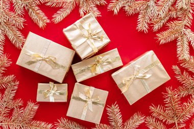 Kırmızı Noel ya da yeni yıl arkaplanı, altın Noel hediyelerinin sade kompozisyonu ve altın köknar dalları, Flatlay, mesajlaşma için boş alan. Noel konsepti.