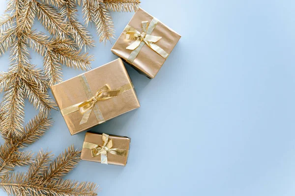 Kék karácsony vagy újévi háttér, egyszerű összetétele arany karácsonyi ajándékok és arany fenyő ágak, Flatlay, üres tér üdvözlő text.christmas koncepció. Stock Kép