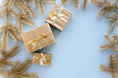 Mavi Noel ya da yeni yıl geçmişi, altın Noel hediyelerinin ve altın köknar dallarının sade kompozisyonu, düzlük, düzlük, mesajlaşma için boş alan. Noel konsepti..