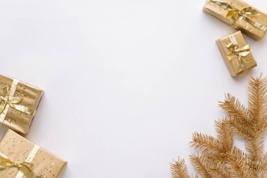 Beyaz Noel veya yeni yıl arkaplanı, altın Noel hediyelerinin ve altın köknar dallarının sade kompozisyonu, düzlük, düzlük, mesajlaşma için boş alan. Noel konsepti.